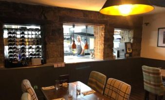 a restaurant with wooden tables and chairs , a wine rack , and a chef in the window at The Punchbowl Inn