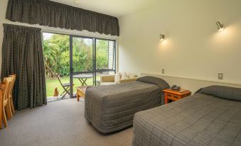 a bedroom with two beds , one on each side of the room , and a sliding glass door leading to a patio at Sunset Motel