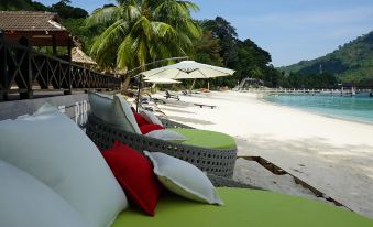 a large white and green bed is on a beach with palm trees in the background at Perhentian Island Resort