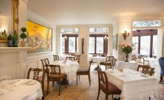 a well - decorated dining room with multiple tables , chairs , and a painting on the wall , creating a warm and inviting atmosphere at Prince of Wales