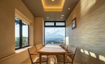 a modern dining room with a wooden table and chairs , large windows offering views of the outdoors , and a scenic mountain view outside at Hotel Clad