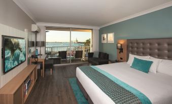 a hotel room with a king - sized bed , a flat - screen tv , and a balcony overlooking the water at Sea World Resort