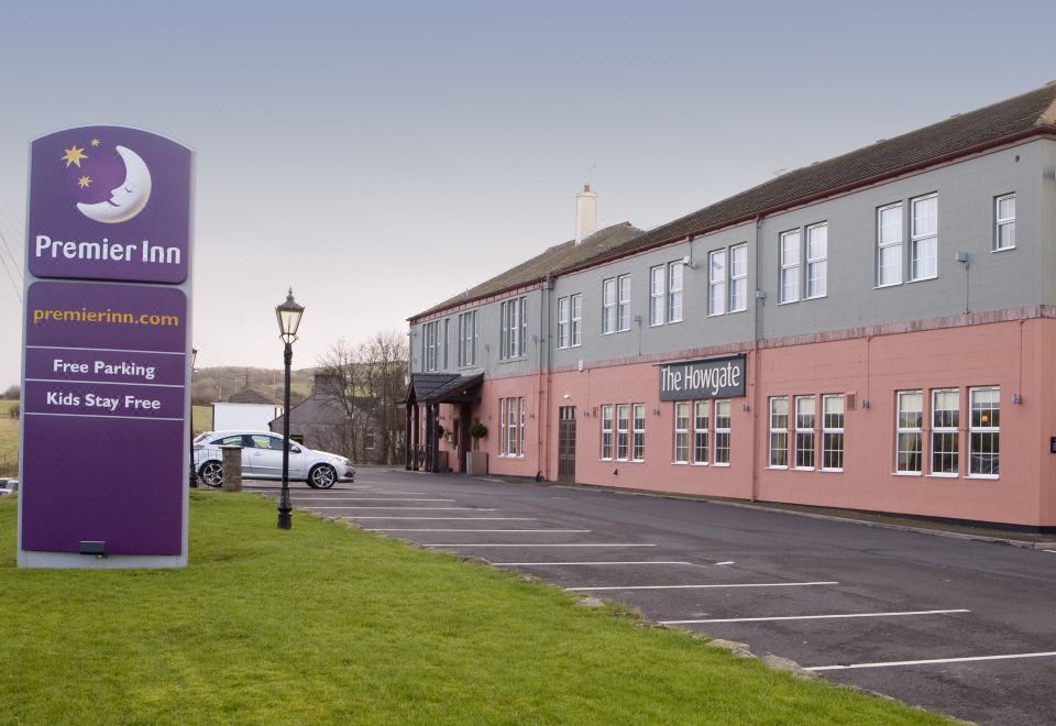 "a car is parked in a lot with a sign and a building with the sign "" the helmville ""." at Premier Inn Whitehaven