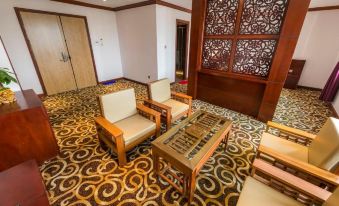 a room with two wooden chairs and a glass coffee table in front of a wall with decorative patterns at Hoang Trung Co to Hotel
