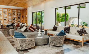 a modern living room with white couches , a large window , and several potted plants at Camino Real Zaashila Huatulco
