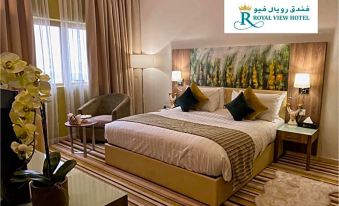 a large bed with white linens and pillows is in a room with a window , table , and chairs at Royal View Hotel