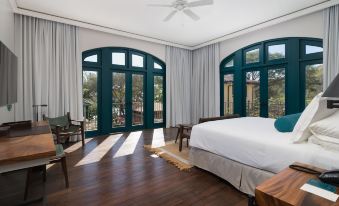 a spacious bedroom with hardwood floors , large windows , and a bed , as well as a balcony view of trees at Santarena Hotel at Las Catalinas