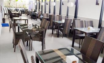 a modern restaurant with a dining area and outdoor seating , featuring wooden tables and wicker chairs at Bromo Park Hotel Probolinggo