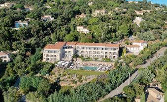 aerial view of a large hotel surrounded by trees , with a pool in the foreground at Hotel la Villa Douce