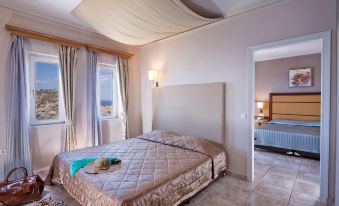 a luxurious bedroom with a king - sized bed , a large window , and a door leading to a balcony at Athina Palace Resort & Spa
