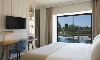 a hotel room with a large bed , a television , and a window overlooking a body of water at Camiral Golf & Wellness - Leading Hotel of the World
