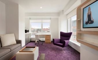 a modern living room with a purple carpet , white walls , and a large window overlooking the city at Yotel Boston