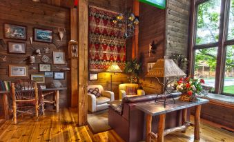a cozy living room with wooden walls , a fireplace , and various furnishings such as a couch , chairs , and a dining table at Drummond Island Resort & Conference Center