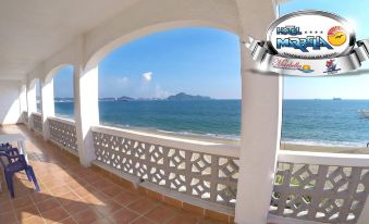 a balcony overlooking the ocean , with a view of the water and mountains in the distance at Hotel Marbella