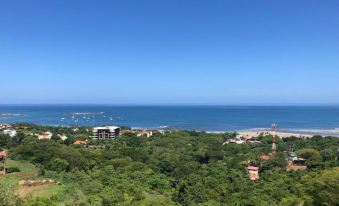 a beautiful view of the ocean from a high vantage point , with lush green trees and buildings in the distance at Wyndham Tamarindo