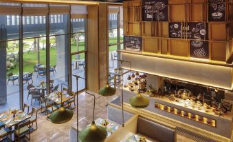 a modern restaurant with a large dining area and a view of the outside through glass doors at Movenpick Resort Cam Ranh