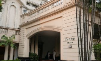 the entrance of a building with a large archway , surrounded by trees and other buildings at The Oberoi Grand Kolkata
