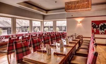 a dining room with a long wooden table covered in red and green plaid tablecloths , surrounded by chairs at Galgorm