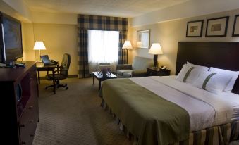 a hotel room with a bed , desk , and chair , as well as a desk with a laptop at Holiday Inn Johnstown-Downtown