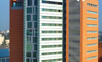 a tall , modern building with a red and white striped facade , situated in a city setting at NH Padova