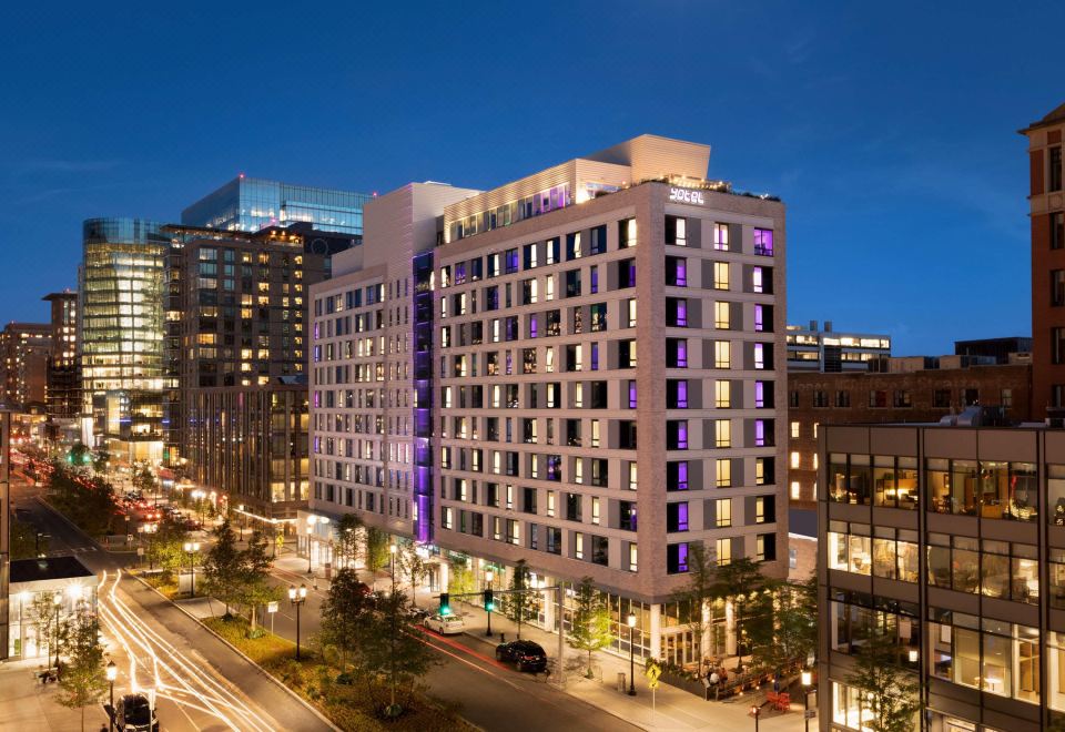 a tall , modern building with many windows and balconies is lit up at night , surrounded by other buildings at Yotel Boston