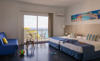 a hotel room with two beds , a table , and a sliding glass door leading to a balcony overlooking the ocean at Htop Caleta Palace #HtopBliss