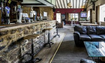 a modern bar with stone walls , wooden ceiling , and various seating arrangements , including stools and tables at Parsonage Farm Inn