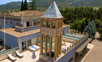 a large , multi - leveled villa with a blue roof and a pool is situated in the mountains at Hotel Ferrero - Singular's Hotels