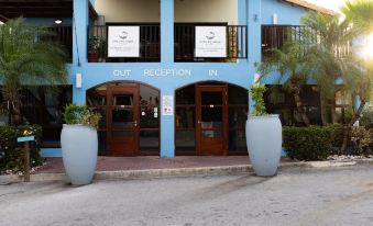 "a blue building with a sign that says "" out reception in "" and two large blue urns on either side of the entrance" at Kunuku Resort All Inclusive Curacao, Trademark by Wyndham