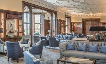 a luxurious hotel lobby with multiple couches and chairs arranged in various positions , creating a comfortable seating area at De Vere Latimer Estate