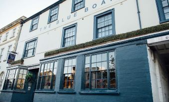 "the exterior of a brick building with blue accents and large windows , featuring the name "" the blue boar "" written on the side" at The Blue Boar