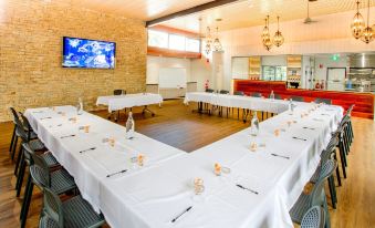 a large dining room with multiple tables covered in white tablecloths , set for a formal dinner at Big4 Gold Coast Holiday Park