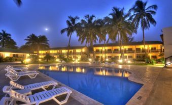 a resort with a large pool surrounded by palm trees and lounge chairs , creating a relaxing atmosphere at Sunset Beach Hotel