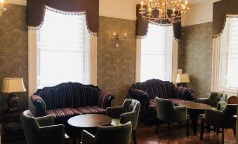 a room with two couches and a dining table , along with a chandelier hanging from the ceiling at Kilmorey Arms Hotel