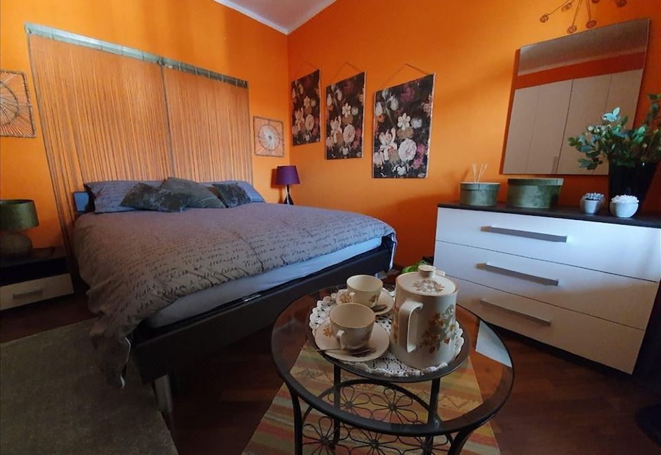 a bedroom with an orange wall , a bed , and a coffee table with a teapot on it at CasAda