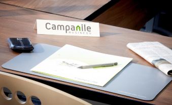 a desk with a note pad , pen , and pen holder , along with a small table in the background at Campanile Paris Est - Bobigny