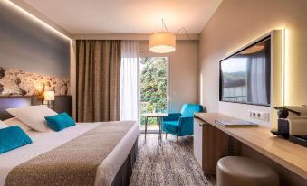a hotel room with a comfortable bed , a flat - screen tv , a desk , and a chair at Mercure Castres l'Occitan