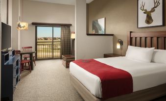 a hotel room with a king - sized bed , a flat - screen tv , and a balcony overlooking a golf course at Great Wolf Lodge Grapevine