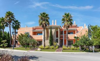 a large orange building with a stone facade and palm trees in front of it at Cascade Wellness Resort