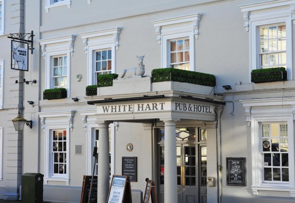 the exterior of a white hart pub and hotel , with the name prominently displayed above the entrance at The White Hart