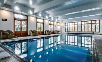 a large indoor swimming pool with a row of lounge chairs and windows in the background at Hotel Bellinzona Daylesford