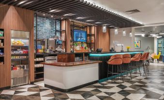 a modern bar with a wooden counter , white and black checkered flooring , and orange chairs at Holiday Inn Leeds - Wakefield M1, Jct.40