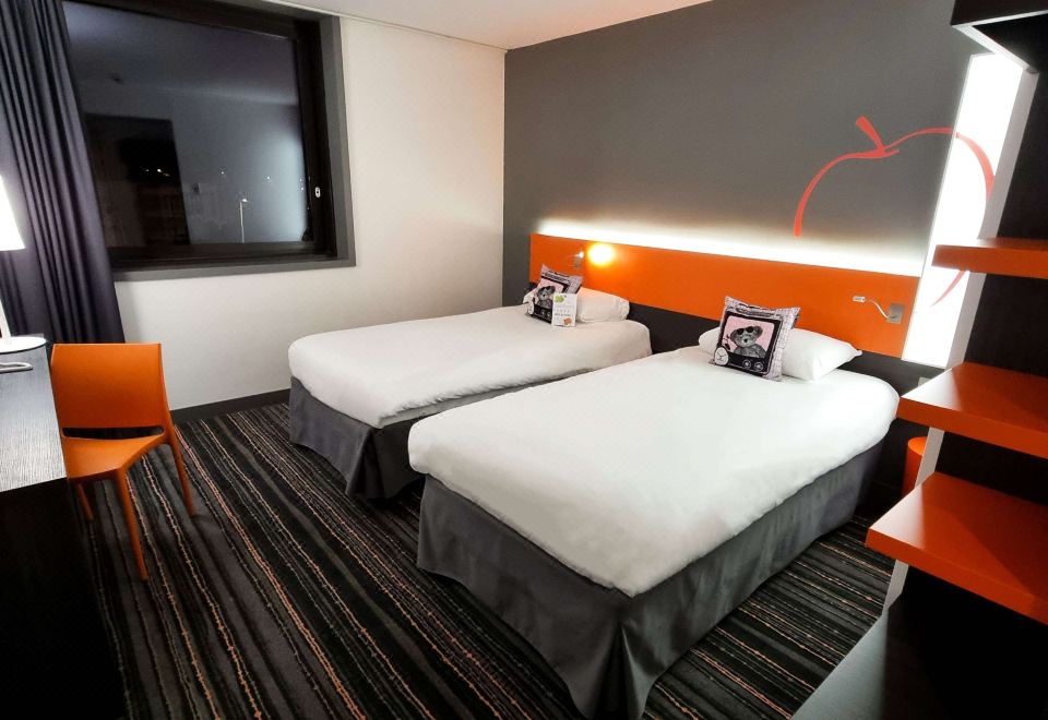 a hotel room with two beds , a window , and an orange headboard , all neatly arranged at Ibis Styles Caen Centre Gare