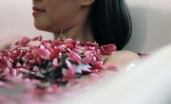 a woman is sitting in a bathtub filled with water and petals , enjoying her time at Tjokro Hotel Klaten