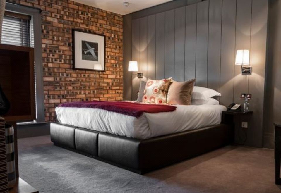 a large bed with a brick wall behind it and two lamps on either side of the bed at Dakota Edinburgh