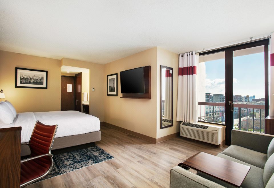 a hotel room with a king - sized bed , a couch , a chair , and a flat - screen tv at Four Points by Sheraton - San Francisco Bay Bridge