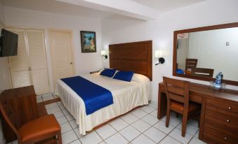 a large bed with a wooden headboard and blue bedding is in a room with a desk , chair , and mirror at Hotel Marbella