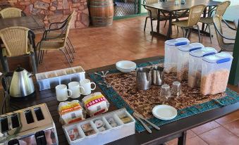 a dining area with a table set for breakfast , complete with cups , plates , and utensils at Parry Creek Farm Tourist Resort & Caravan Park