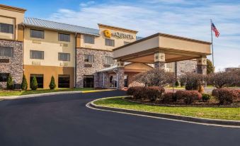 an exterior view of a la quinta inn & suites hotel , with a large building in the background at La Quinta Inn & Suites by Wyndham Fairborn Wright-Patterson