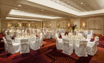 a large , elegant banquet hall with multiple dining tables covered in white tablecloths and adorned with elegant centerpieces at Crowne Plaza Englewood, an IHG Hotel